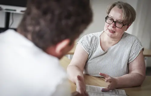 Beratung im Berufsvorbereitungslehrgang "Praxislernprojekt": Die Berufseinstiegscoachin bespricht mit einem jungen Mann einen persönlichen Lern- und Förderplan für seine Ausbildung.